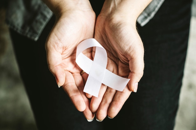 Closeup of white ribbon on hands palm bone cancer anti violence awareness