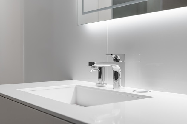 Closeup of white sink with large and small taps for filtering drinking running water concept of