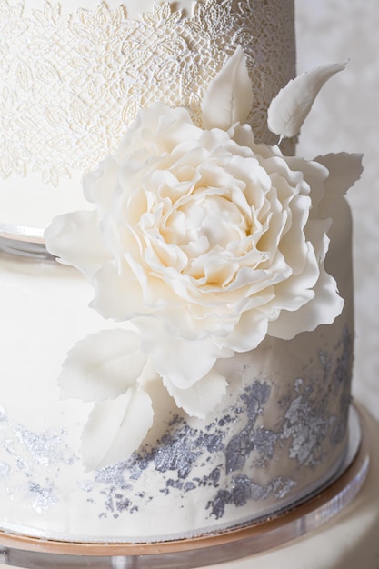 The closeup of a white sugar rose on a wedding cake the\
wonderful marzipan on a threetiered cake