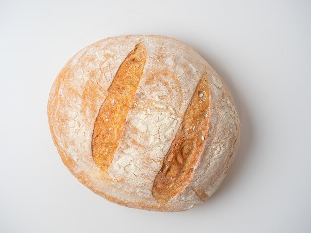 A closeup of a whole fresh crispy delicious roundshaped wheat bread on a white background Insulated items baking top vew