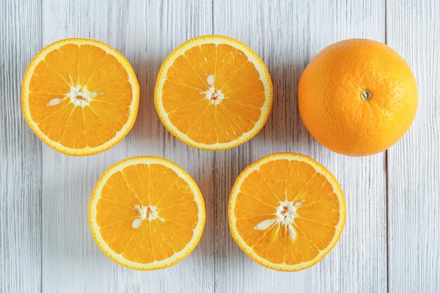 Closeup of whole and sliced oranges on a light wooden surface selective focus