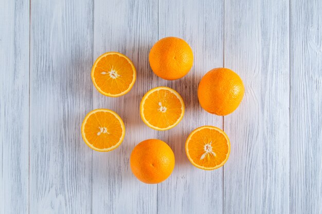 Closeup of whole and sliced oranges on a light wooden surface