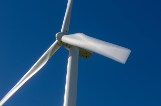 Closeup of a wind turbine turning at full power under a completely blue and cloudless sky