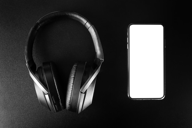 Closeup of wireless headphones smartphone with blank screen isolated on white background mock up