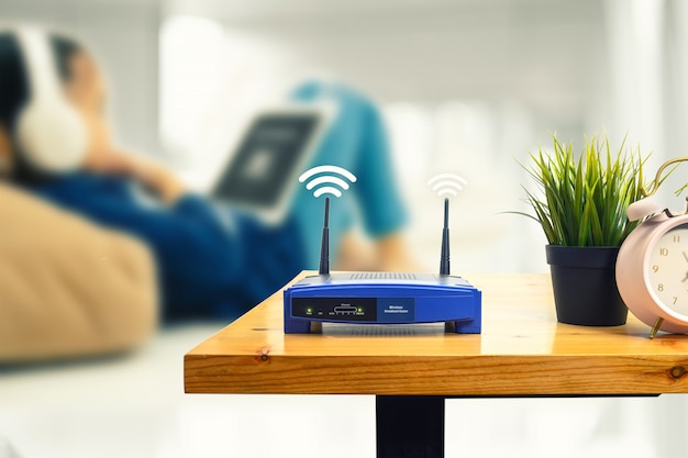 Photo closeup of a wireless router and a man using smartphone on living room at home office