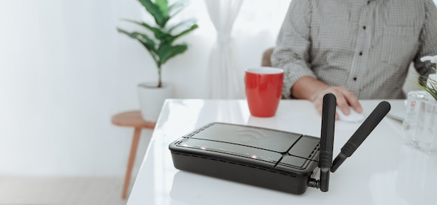 Foto primo piano di un router wireless e un uomo che per mezzo dello smartphone sul ofiice del salone a casa.