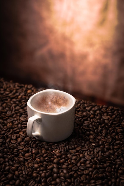 Closeup with the cup of coffee on top of the grains and the defocused illuminated background
