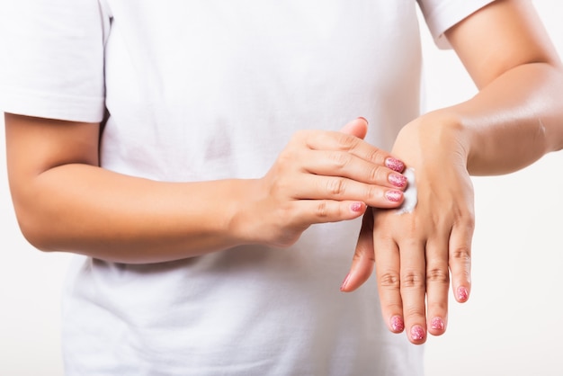 Closeup woman applying lotion cosmetic moisturizer cream on her behind the palm skin hand