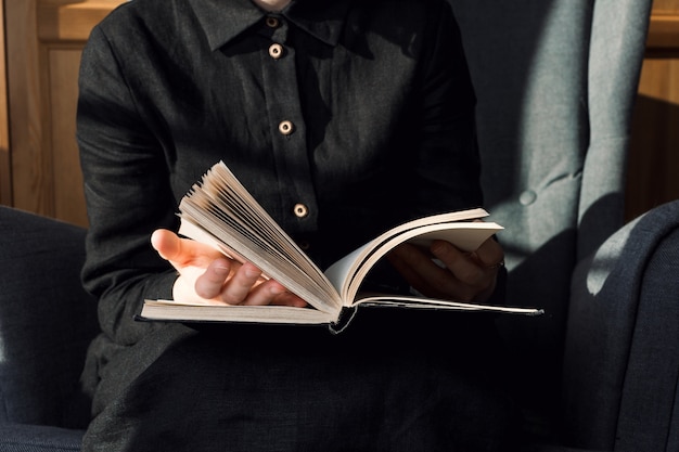 Closeup of woman in black dress holding book on her lap