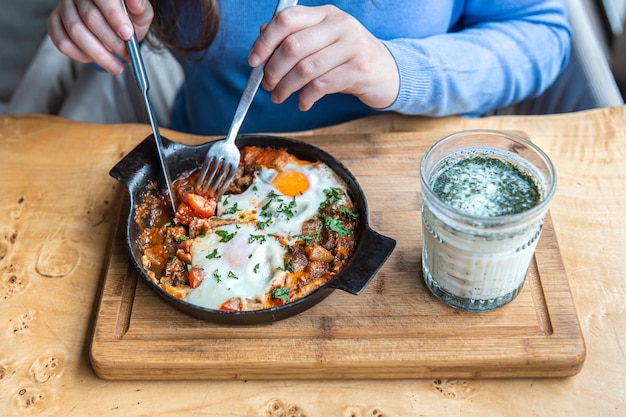 伝統的なシャクシューカで食事をするカフェの女性をクローズアップ