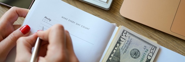 Closeup of woman counting money and making notes in notepad earned money savings and earnings