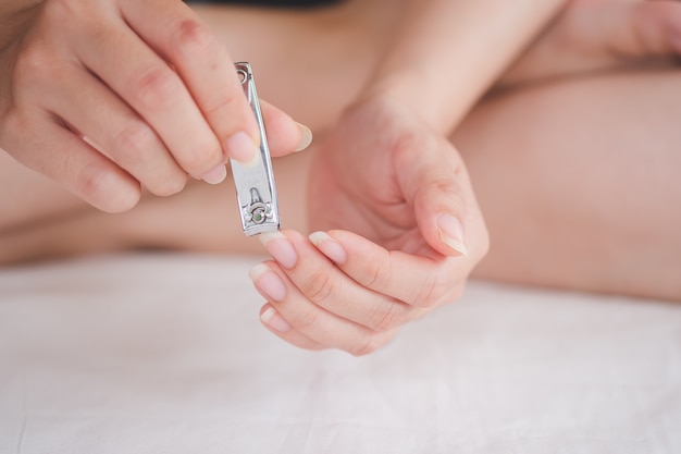 Primo piano di una donna che taglia le unghie, concetto di assistenza sanitaria, messa a fuoco selettiva.