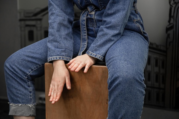 Primo piano una donna in abito di jeans suona il cajon Foto Premium