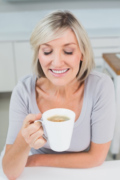 Closeup of a woman drinking coffee in kitchen