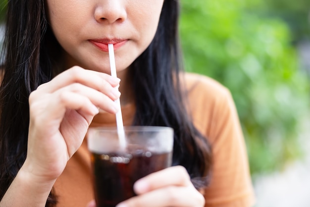 写真 氷のコーラを飲むクローズアップの女性。食べ物や飲み物のコンセプト。