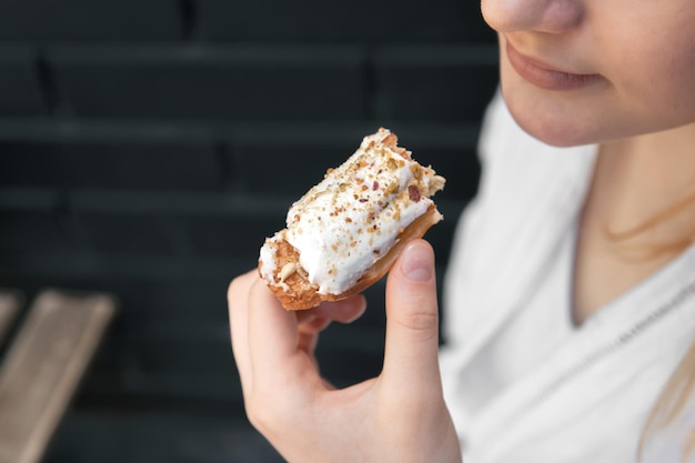 Closeup a woman eats an appetizing eclair