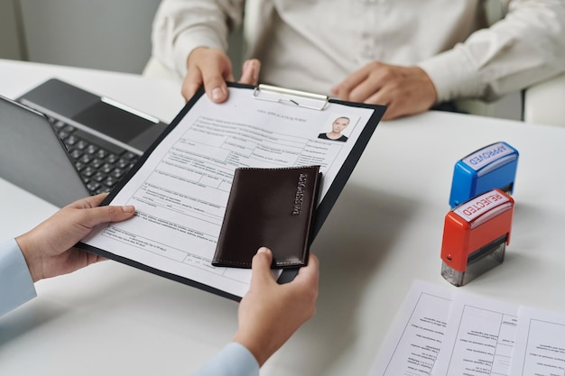 Closeup of woman giving documents to get visa in visa center