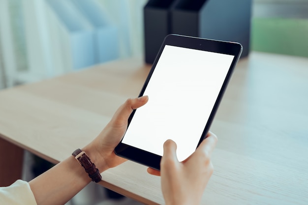 Closeup of woman hand holding digital tablet on the table and the screen is blank.