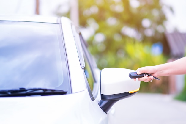 Mano della donna del primo piano che tiene i sistemi di allarme dell'automobile del telecomando