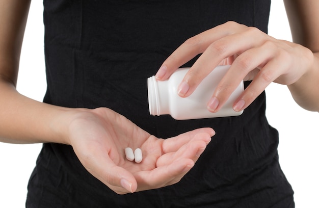 Closeup woman hand pouring white pills into her hand.