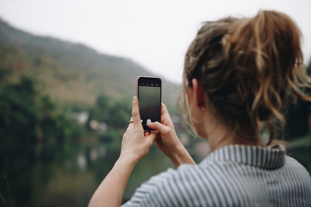 彼女のスマートフォンを上げる女性の手の写真の写真を撮る