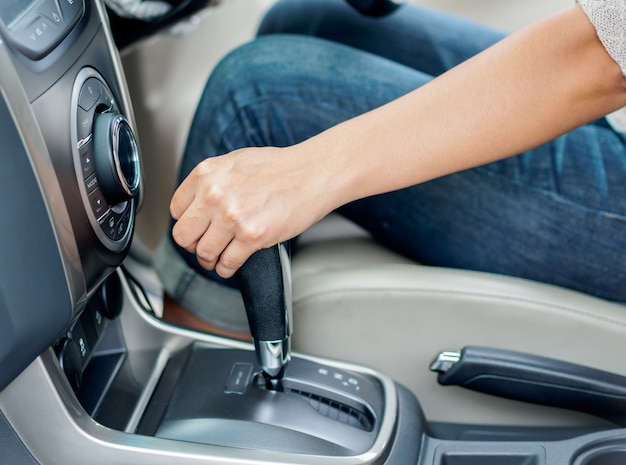 Mano della donna del primo piano che sposta la leva del cambio e che conduce un'automobile