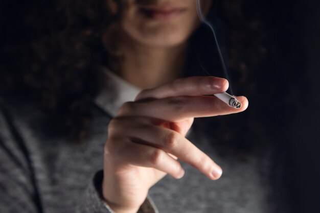 Closeup woman hand smoking cigarette, unhealthy lifestyle concept