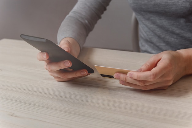 Photo closeup woman hand use phone and credit card on table.