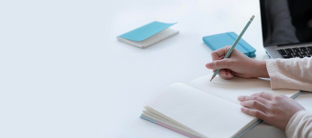 Closeup woman hand using pencil writing on blank notebook pagge copy space