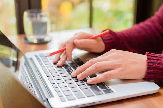 Mano della donna del primo piano che lavora al suo computer portatile.