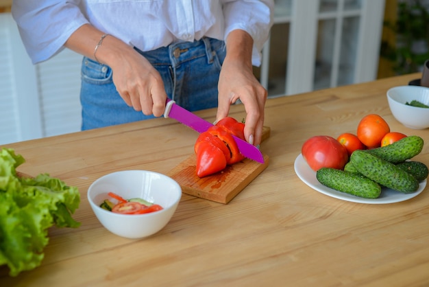 Closeup woman hands chopping cucumber vegetables by knife