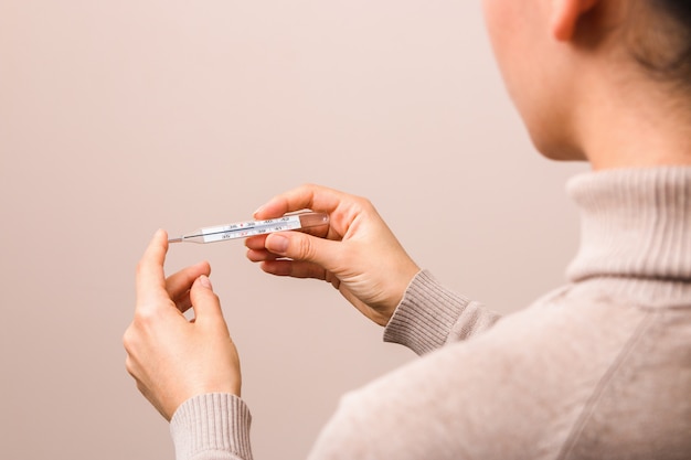 Closeup woman hands holding a glass thermometer with high temperature above thirty eight. coronavirus symptoms