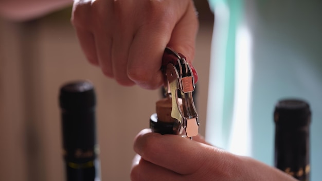 Closeup of woman hands opening bottle of wine using corkscrew sommelier or waiter in restaurant