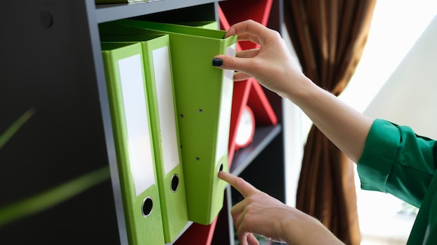 Photo closeup of woman hands taking off green paper folder archive paperwork and office work business