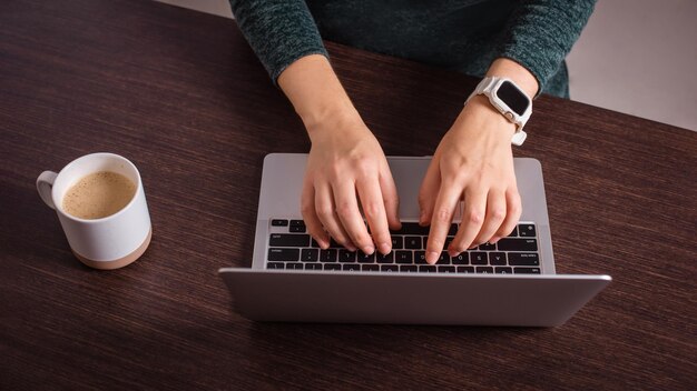 closeup woman hands typing on laptop keyboard working at home