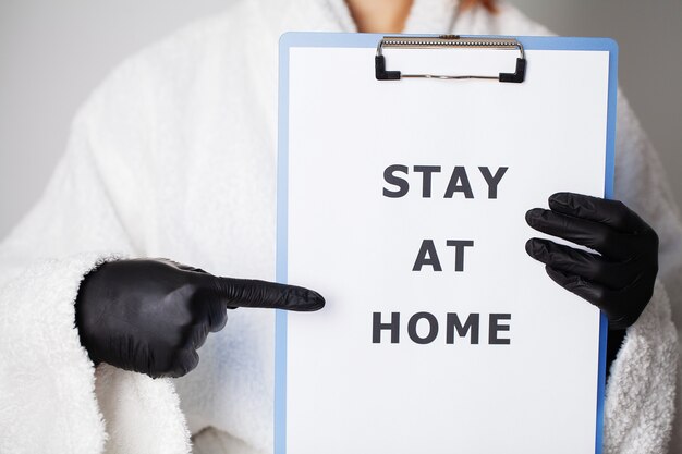 Closeup of woman holding blank with inscription stay at home calling for stop spreading covid-19