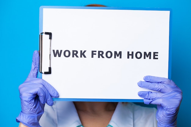 Foto primo piano della donna che tiene in bianco con il lavoro dell'iscrizione dalla casa che richiede la fermata di diffusione covid-19