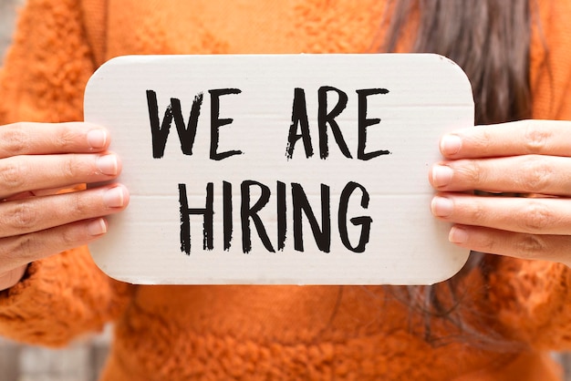 closeup woman holding a card with we are hiring concept