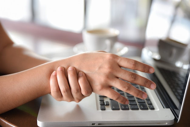 Closeup woman holding her hand pain from using computer long time. Office syndrome concept.