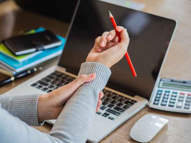 Closeup woman holding her wrist pain from using computer long time. Office syndrome concep