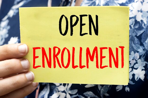 closeup woman holding a yellow card with open enrollment