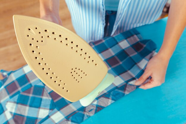 Closeup of woman ironing clothes on ironing board