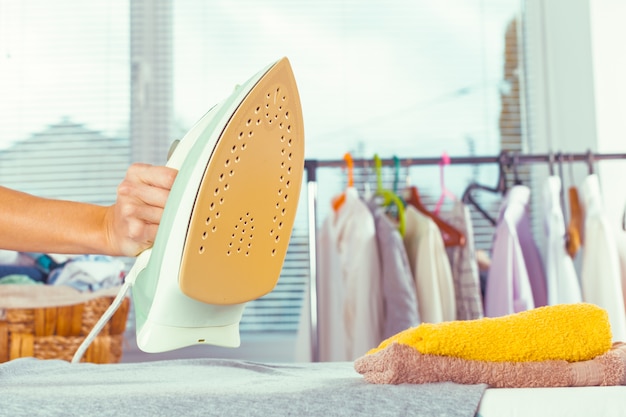 Closeup of woman ironing clothes on ironing board