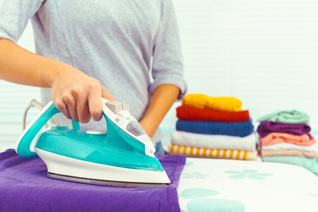 Closeup of woman ironing clothes on ironing board