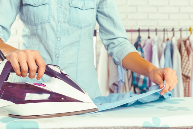 Closeup of woman ironing clothes on ironing board