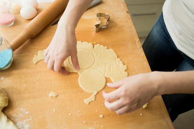 Closeup of woman making cookies cutting dough with mold
