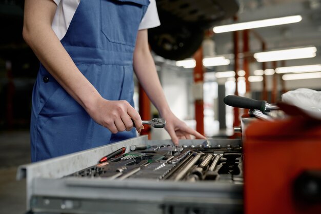 Closeup woman mechanic hands choosing correct tool for car repair of inoperative engine and failure troubleshooting