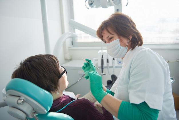 Крупный план пациентки у дантиста, ожидающей осмотра с женщиной-врачом на заднем плане