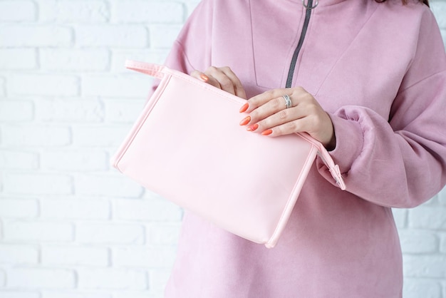 Closeup woman in pink clothes hands holding pink toiletry bag for mockup