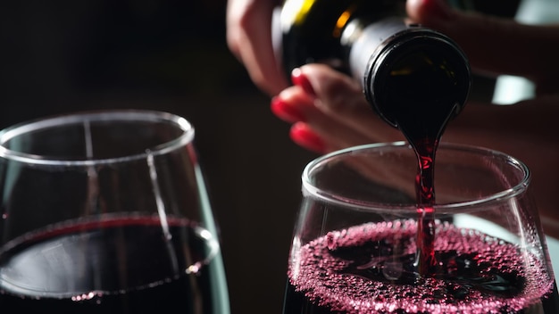 Closeup of woman pouring red wine into glass tasting and degustation sommelier restaurant or